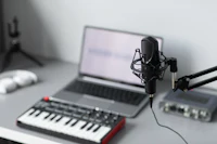 a microphone sits on a desk next to a keyboard and laptop