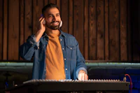 a man in a beard is standing in front of a music keyboard